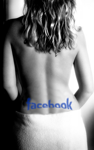 Black and white photo of a Facebook tatooed on the lower back of a woman