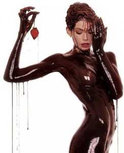 Naked Woman covered in chocolate holding a strawberry